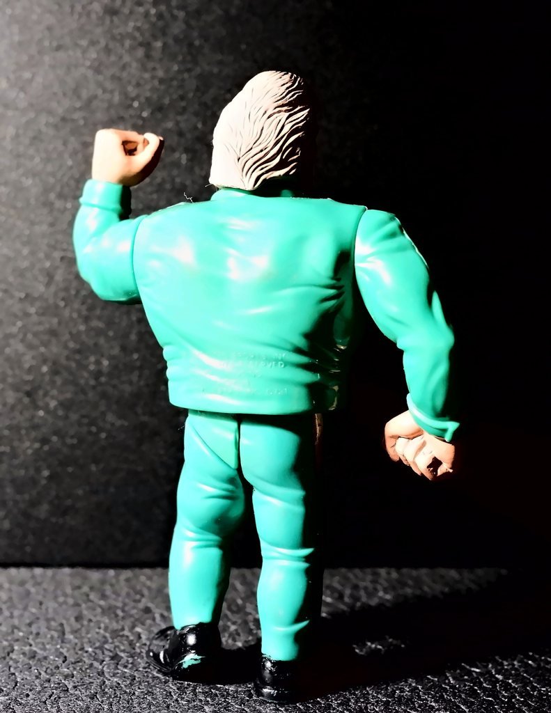 Ted DiBiase di spalle, con il pugno sinistro alzato e, in basso sulla giacca, le scritte della Titan Sports e della Hasbro