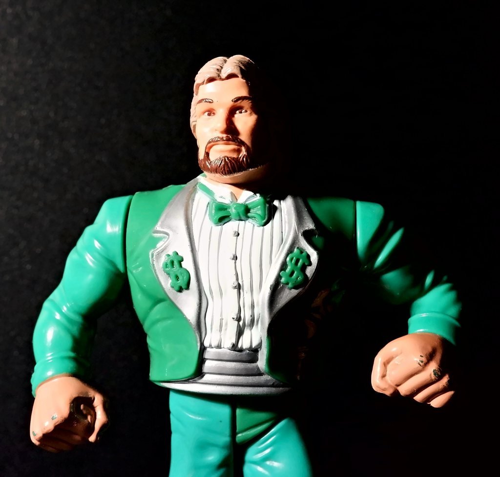 Il busto di Ted DiBiase: papillon verde, camicia plissettata e due simboli del dollaro sui risvolti