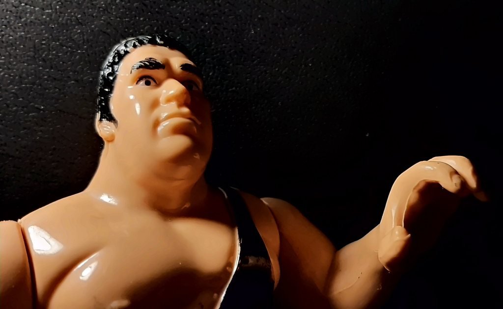 André the Giant visto dal basso, con lo sguardo rivolto in alto e la mano sinistra aperta ad artiglio