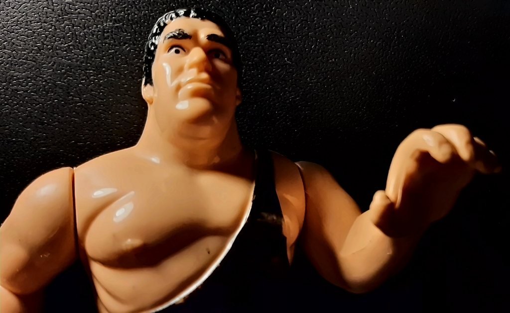 André the Giant di fronte, con la mano sinistra alzata e aperta ad artiglio