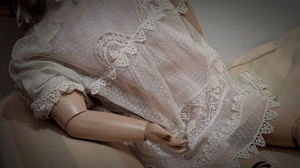 L’abito di tulle a pois con gli inserti di pizzo e il braccio destro snodato al gomito e al polso