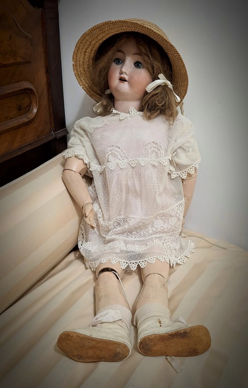 La bambola seduta di fronte, con le gambe distese sul divano letto