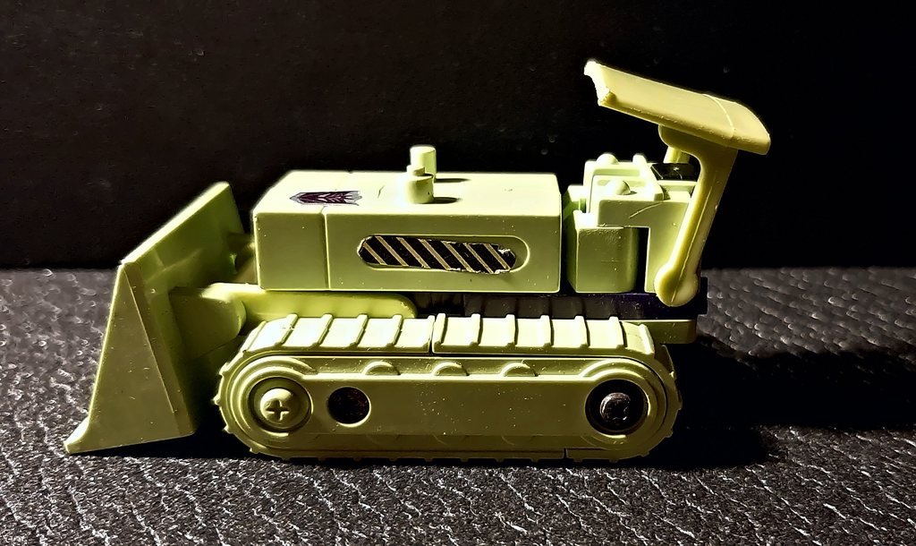 Il bulldozer di fianco, con i cingoli e il tettuccio
