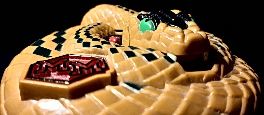 Il guscio chiuso visto di lato, all'altezza del distintivo “MM”: gli occhi verdi e le zanne bianche del serpente